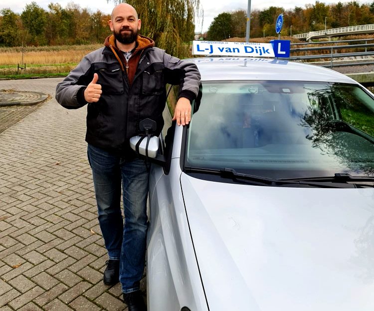 Laurens-Jan van Dijk bij zijn lesauto met daklicht in Almere