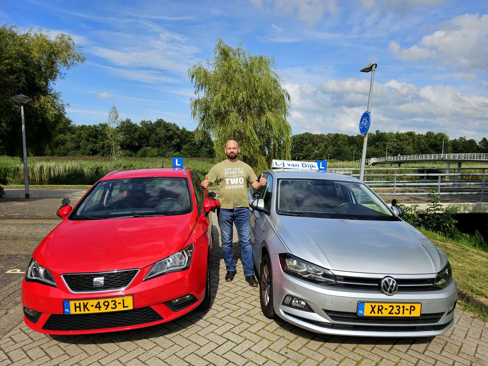 Laurens-Jan van Dijk tussen zijn twee lesauto's met L-plaat in Almere